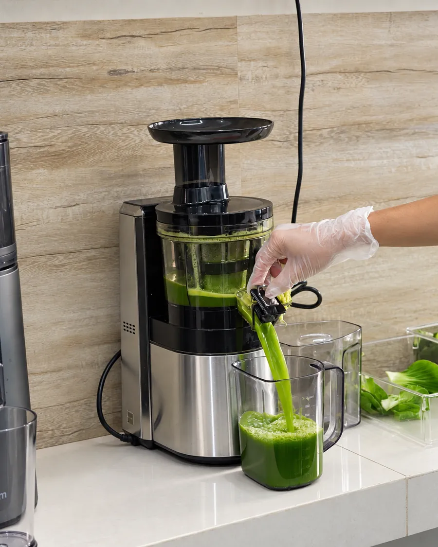 Mesin cold press memeras sayur hijau menjadi jus segar di pagi hari